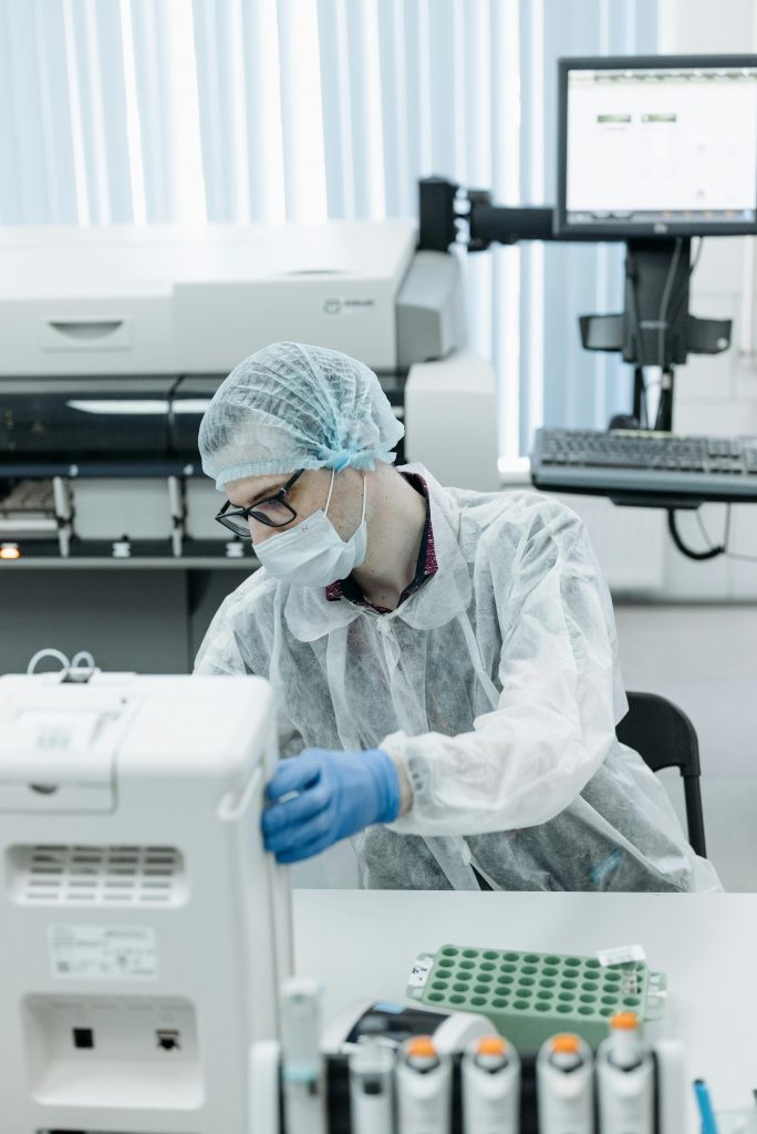 Scientist in protective gear operating equipment in a modern laboratory.
