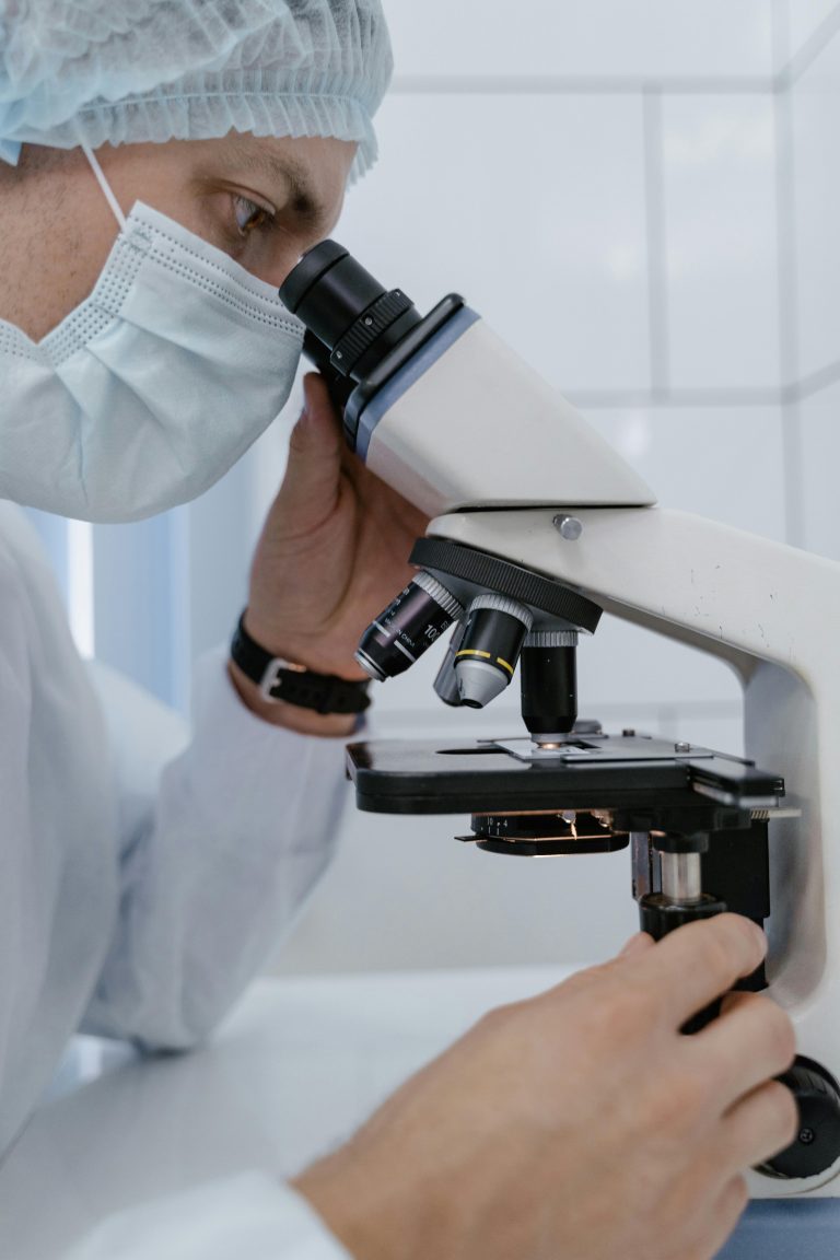A scientist uses a microscope to examine samples in a laboratory setting, showcasing research equipment.